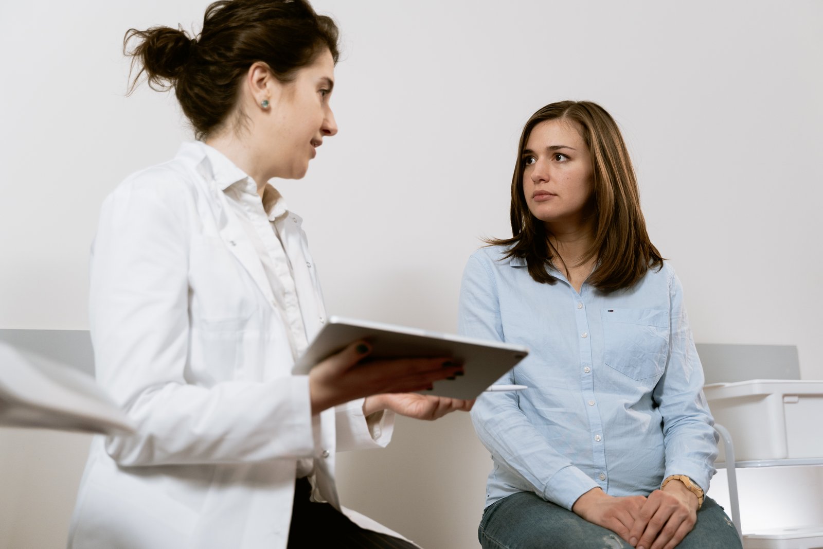 Eine Frau sitzt beim Frauenarzt und spricht mit ihr
