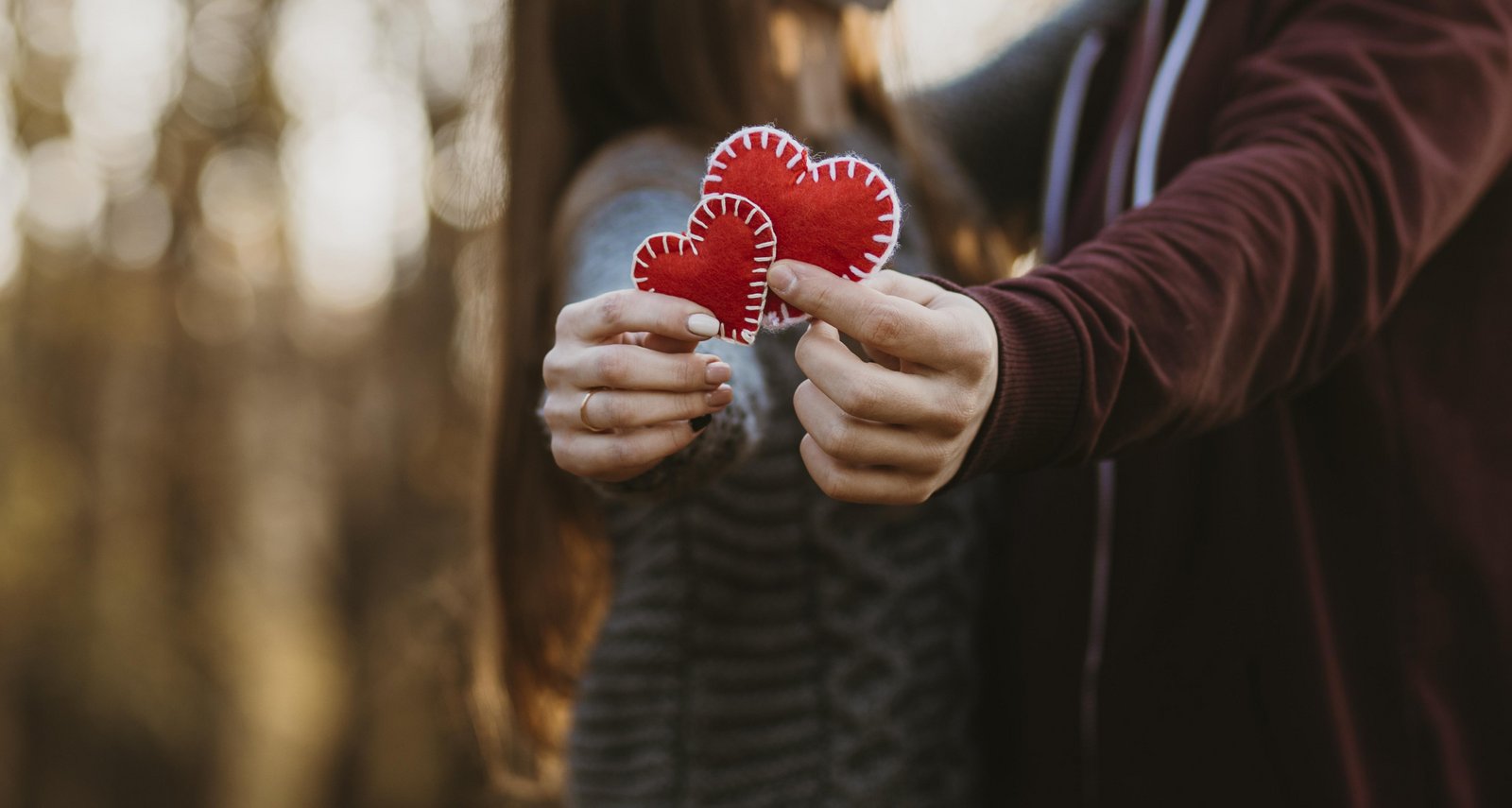 Un couple d'amoureux tient deux cœurs rouges dans la main pour la Saint-Valentin