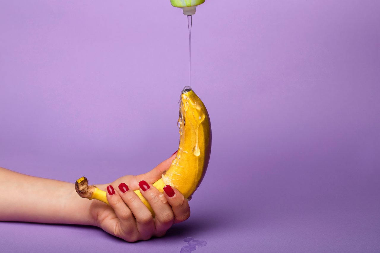 Il lubrificante viene fatto scorrere su una banana tenuta con una mano.